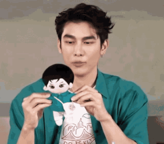 a man in a green shirt is holding a stuffed toy in his hands .