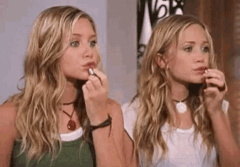 two women are applying lipstick to each other 's lips .
