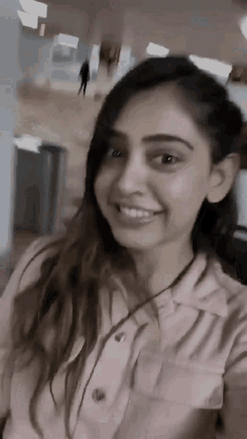 a woman in a pink shirt is taking a selfie with her phone .