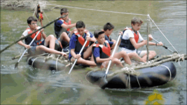 a group of boys are rowing a raft in a river