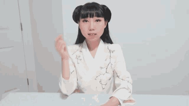 a young woman in a kimono is sitting at a table making a funny face .