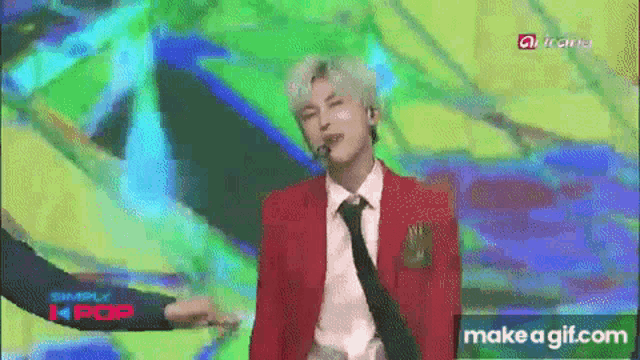 a man in a red suit and tie is dancing on a stage in front of a make a gif.com logo