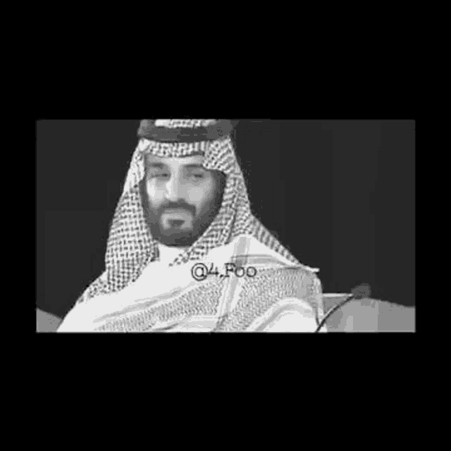 a black and white photo of a man with a beard wearing a keffiyeh and a scarf .