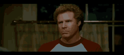 a man with curly hair is wearing a red and white shirt and making a funny face .
