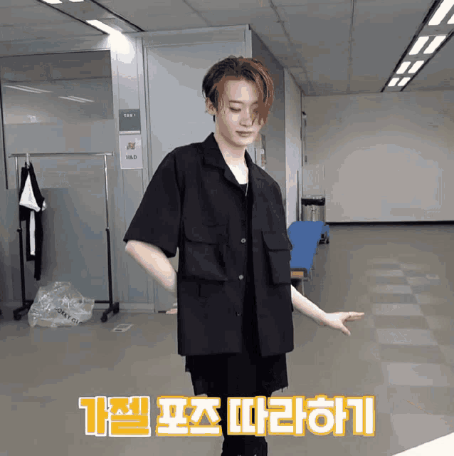 a man in a black shirt is standing in a room with korean writing on the floor
