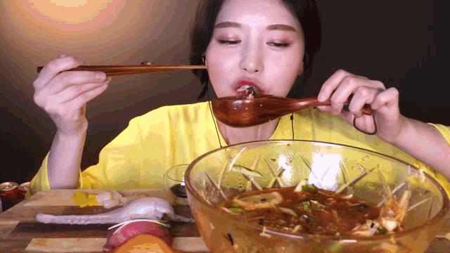 a woman is eating a bowl of soup with chopsticks .