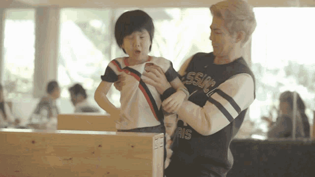 a man in a sweater that says ' ssu ' on it is holding a child