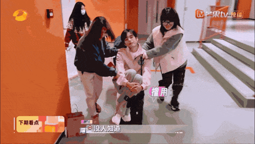 a group of people are standing around a person with chinese writing on the screen