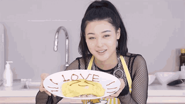 a woman is holding a plate of food with the word love written on it