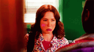 a woman in a floral shirt is making a funny face while talking to a man .
