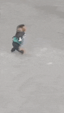 a person is crawling under the rear end of a white car .