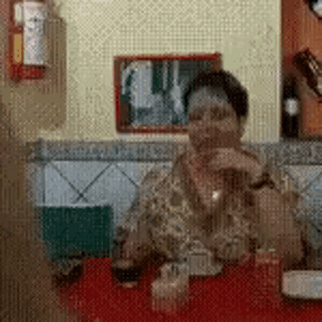 a woman is sitting at a red table with a glass of wine in front of her .