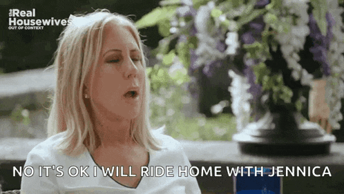 a woman says " no it 's ok i will ride home with jennica " in front of a vase of flowers