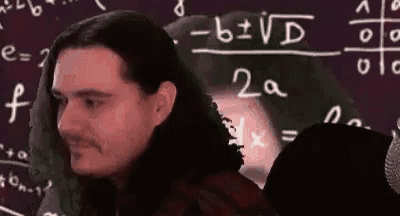 a man with long hair is sitting in front of a blackboard with math equations .