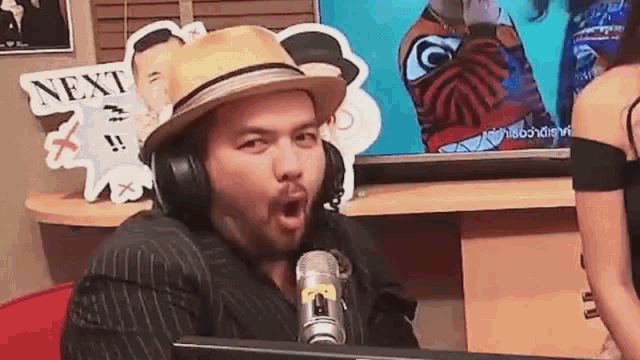 a man wearing a hat and headphones is sitting in front of a microphone ..