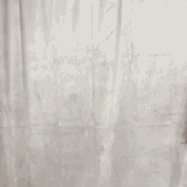 a woman with long hair is standing in front of a white curtain and making a funny face .