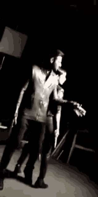 a man and a woman are walking on a stage in a dark room .