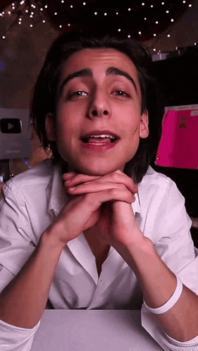 a young man in a white shirt is looking at the camera