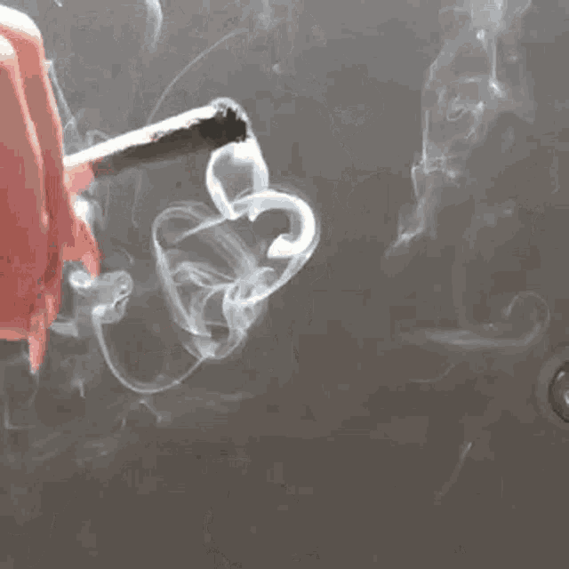 a woman with long pink nails is smoking a cigarette .