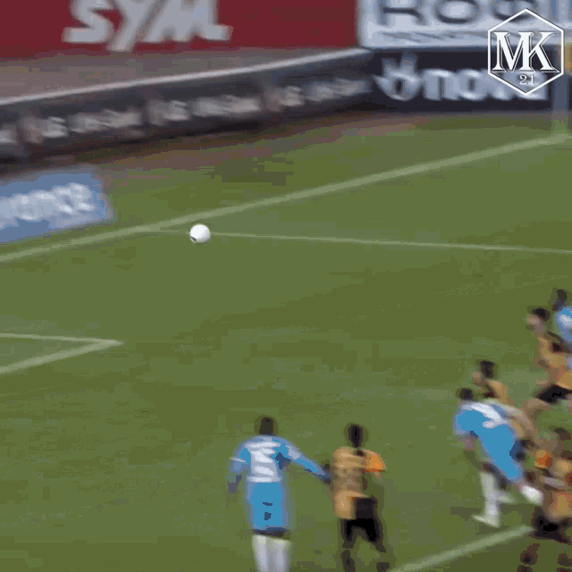 a soccer player jumps to catch a ball in front of a sign that says mk