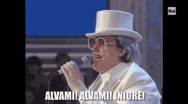 a man in a top hat is singing into a microphone while wearing sunglasses .