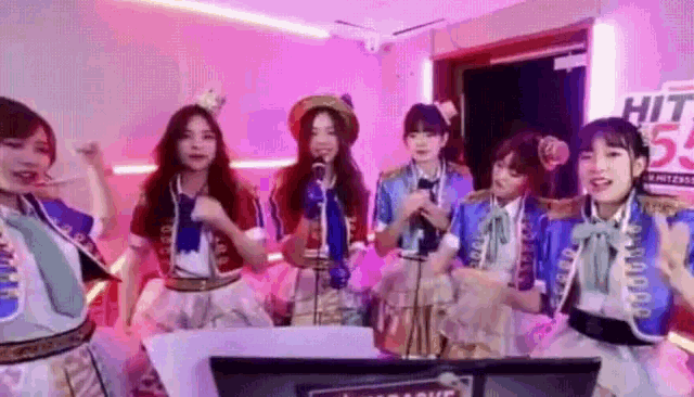 a group of girls singing in front of a sign that says hit 55.5