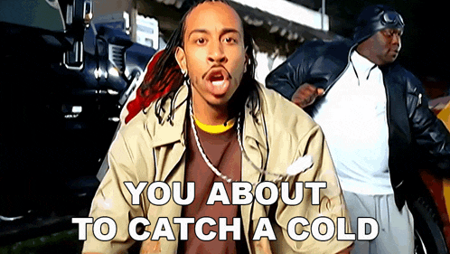 a man with dreadlocks is standing in front of a sign that says " you about to catch a cold "