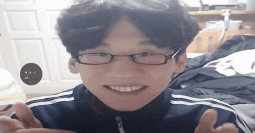a young man wearing glasses and a blue jacket is smiling