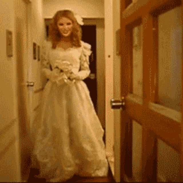 a woman in a wedding dress is standing in front of a door