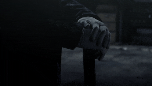 a person 's hand is holding a cane in a dark room