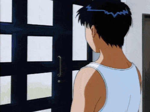 a man in a blue tank top stands in front of a black door