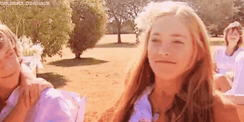 a woman with long red hair is sitting in a park with a group of people .