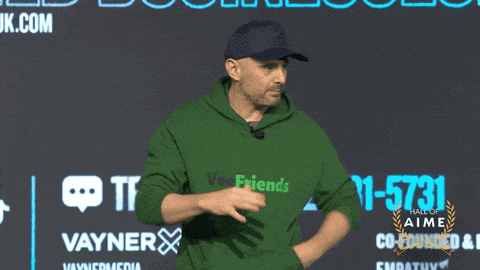 a man in a green hoodie stands in front of a wall that says vayner on it