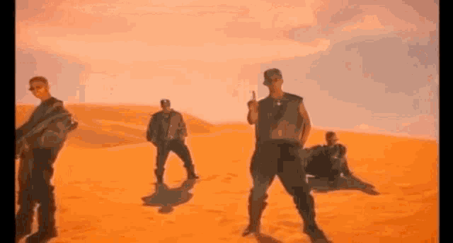 a group of men are dancing in the desert .