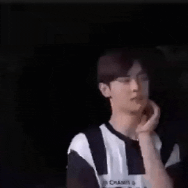 a man in a black and white striped shirt is touching his face .