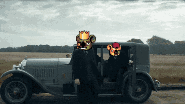 a man in a suit with a crown on his head stands next to an old car