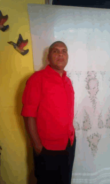 a man in a red shirt is standing in front of a yellow wall