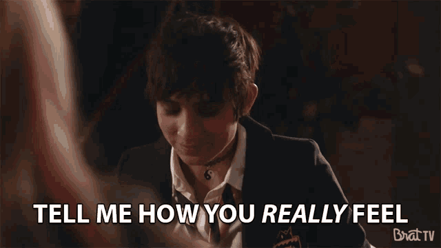 a girl in a suit and tie is talking to another girl and says " tell me how you really feel "