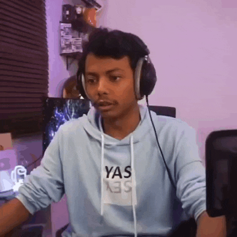 a man wearing headphones and a hoodie is sitting in front of a computer .