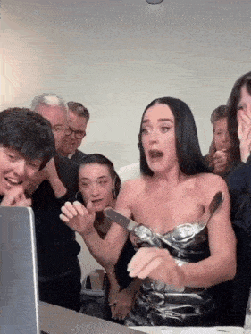a group of people are gathered around a woman in a black dress