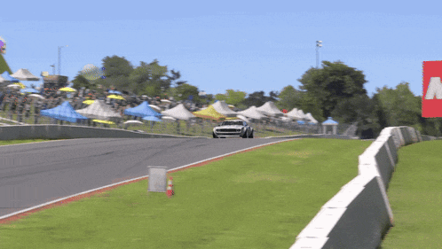 a white car is driving down a race track with a sign that says m on it