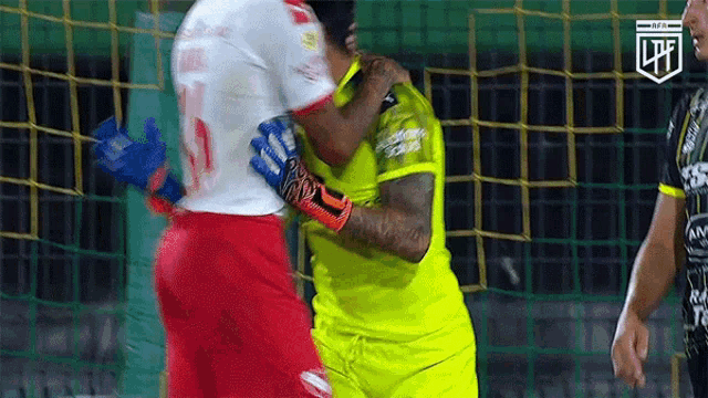 a soccer player in a yellow jersey is hugging another player in a white jersey .