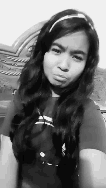 a black and white photo of a young girl making a face .