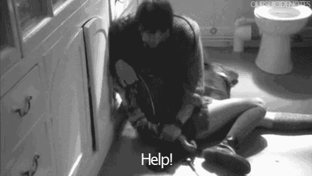a black and white photo of a man and a woman kneeling on the floor in a bathroom .