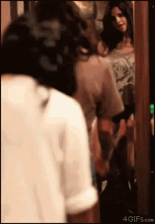a woman is standing in front of a mirror and looking at herself in the mirror