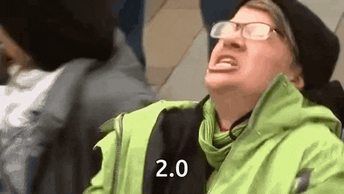 a man wearing glasses and a green jacket is making a funny face while sitting on a bus .