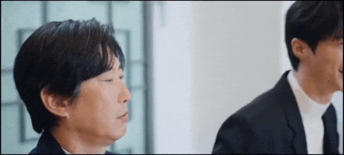 two men in suits are standing next to each other in a room .