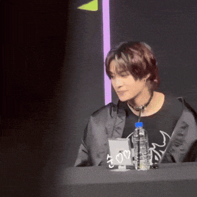 a man sitting at a table with a bottle of water and a sign that says ' i love you '