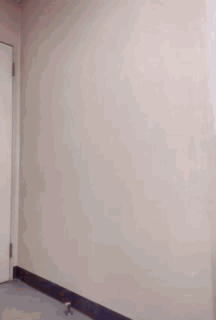 a person is standing in a hallway next to a door holding a piece of paper