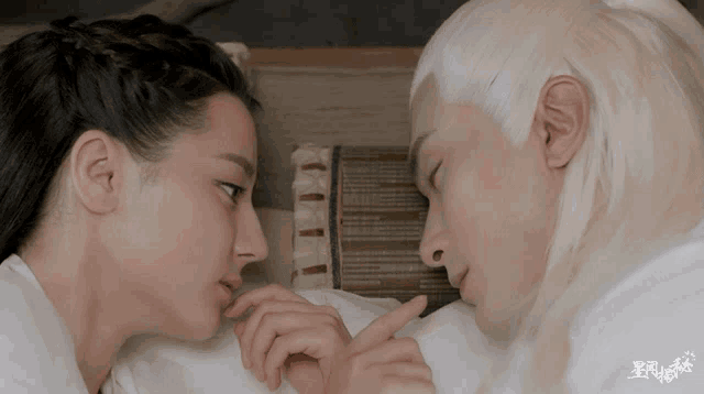 a man and a woman are laying face to face and the man is pointing at the woman 's finger